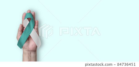 Teal and white ribbon for cervical cancer awareness month in January and HPV prevention with bow on hand support 84736451