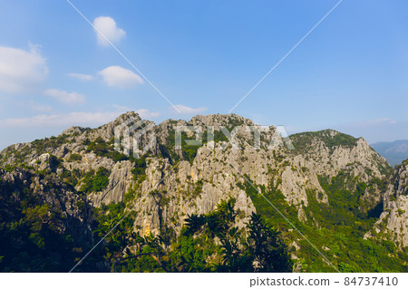 Scenic landscape view of limestone mountain with cliff in tropical forest. Scenic landscape view of limestone mountain with cliff in tropical forest. 84737410