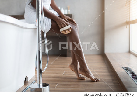 Unrecognizable black woman massaging her legs at bathroom 84737670