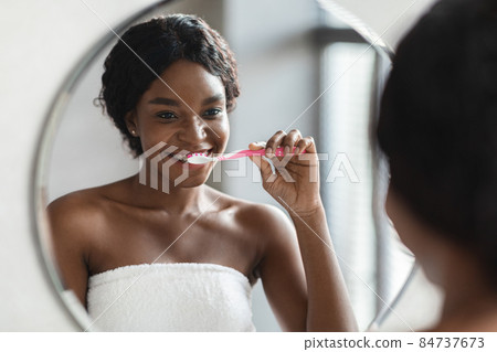 Young black woman with braces brushing her teeth 84737673