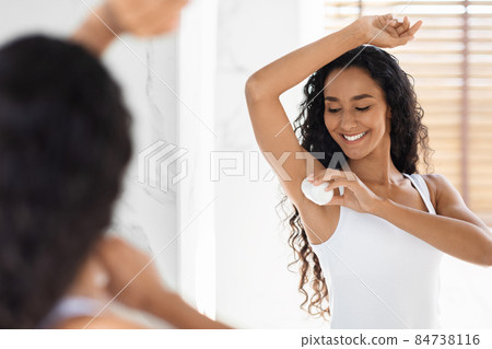 Beautiful Young Woman Applying Roller Deodorant To Armpit Zone In Bathroom 84738116