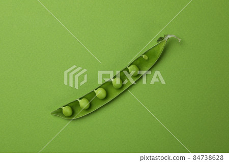 Green pea pod with seeds on green background Green pea pod with seeds on green background 84738628