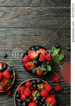 Bowls with berry mix and juice on wooden background Bowls with berry mix and juice on wooden background 84739514