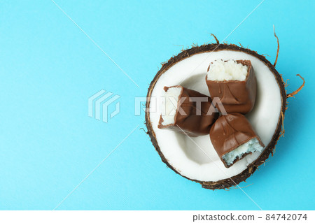 Coconut with candy bars on blue background Coconut with candy bars on blue background 84742074