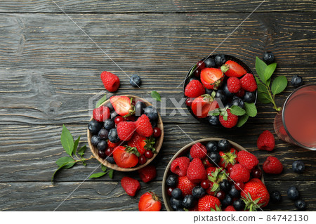 Bowls with berry mix and juice on wooden background 84742130
