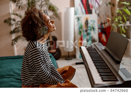 Cheerful young woman sitting near synthesizer at home 84742668
