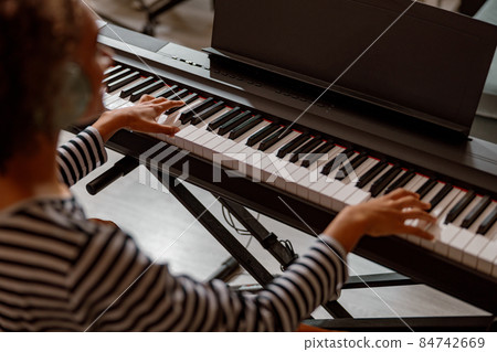 Multiracial young woman playing synthesizer at home 84742669