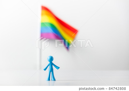 Plastic figure and LGBT rainbow flag on light gray background 84742808