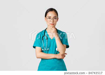 Covid-19, healthcare workers, pandemic concept. Serious-looking young female internet, asian nurse or physician in scrubs and glasses thinking, pondering or making choice, examine patient Covid-19, healthcare workers, pandemic concept. Serious-looking young female internet, asian nurse or physician in scrubs and glasses thinking, pondering or making choice, examine patient 84743517