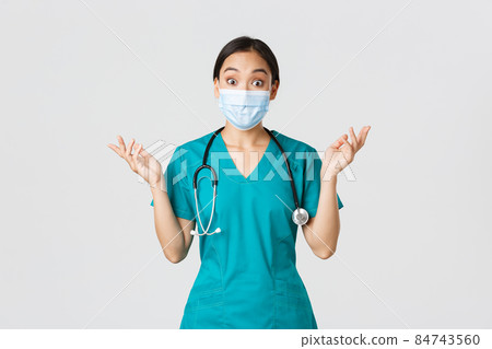 Covid-19, coronavirus disease, healthcare workers concept. Surprised and amazed asian female nurse, physician in medical mask and scrubs raising hands up excited, hear amazing news, white background Covid-19, coronavirus disease, healthcare workers concept. Surprised and amazed asian female nurse, physician in medical mask and scrubs raising hands up excited, hear amazing news, white background 84743560