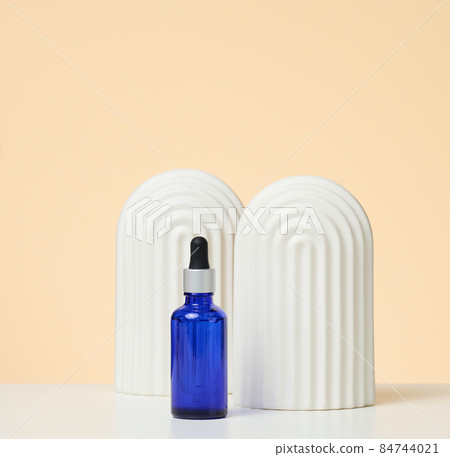 blue glass bottle with pipette stands on a beige background. Cosmetics SPA branding. Packaging for gel, serum, advertising and product promotion 84744021