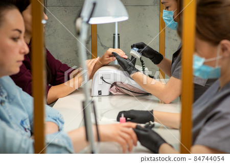 Two women getting a manicure treatment in beauty salon. Two women getting a manicure treatment in beauty salon. 84744054