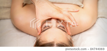 Face massage with fingers of a masseur. Female facial skin care at a beauty spa salon. 84744069