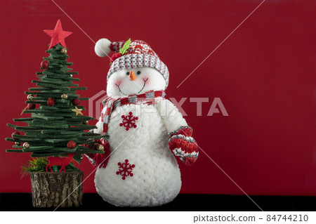 Christmas greeting background with pine tree and Snowman ornaments isolated on red surface with copy space 84744210