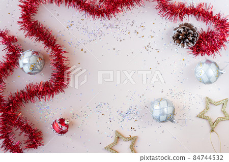 Flat lay xmas composition with empty space. Red tinsel, golden stars, silver Christmas balls and glitter with bokeh lights. New Year backplate for your design or postcard. Happy holidays concept Flat lay xmas composition with empty space. Red tinsel, golden stars, silver Christmas balls and glitter with bokeh lights. New Year backplate for your design or postcard. Happy holidays concept 84744532