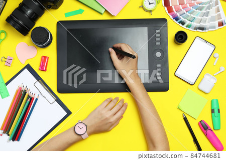 Flat lay composition with graphic drawing tablet and different office items on grey stone background 84744681