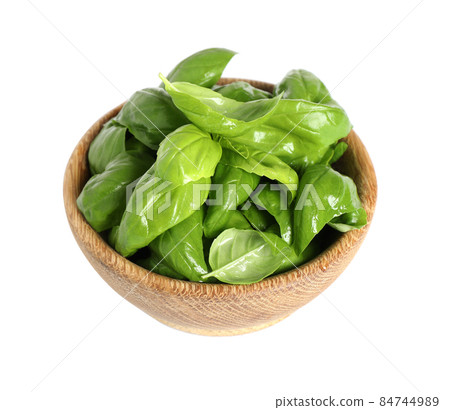 Fresh green basil leaves in wooden bowl isolated on white Fresh green basil leaves in wooden bowl isolated on white 84744989