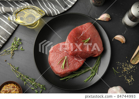 Flat lay composition with fresh beef cut on black table 84744993