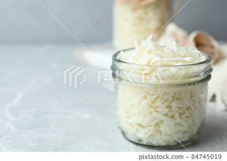 Tasty fermented cabbage on light grey marble table, closeup 84745019