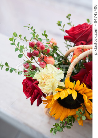 Top view. Part of a basket with beautiful autumn flowers made of red roses, sunflowers and green leaves, with barberry berries. The concept of the holiday. Copy space. High quality photo Top view. Part of a basket with beautiful autumn flowers made of red roses, sunflowers and green leaves, with barberry berries. The concept of the holiday. Copy space. High quality photo 84745406