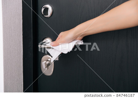Cleaning black door handles with an antiseptic wet wipe. Woman hand using towel for cleaning home room door link. Sanitize surfaces prevention in hospital and public spaces against corona virus. 84746187