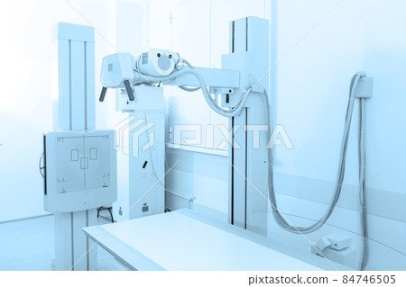X-ray department in modern hospital. Radiology room with scan machine with empty bed. Technician adjusting an x-ray machine. Scanning chest, heart, lungs in modern clinic office. X-ray department in modern hospital. Radiology room with scan machine with empty bed. Technician adjusting an x-ray machine. Scanning chest, heart, lungs in modern clinic office. 84746505