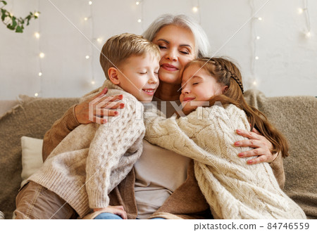 Loving senior grandmother hugging cute happy grandchildren during winter holidays at home 84746559