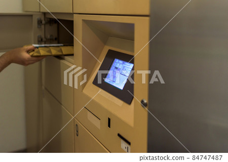 從公寓的卡片式包裹投遞箱接受包裹投遞服務的男性。 從公寓的卡片式包裹投遞箱接受包裹投遞服務的男性。 84747487
