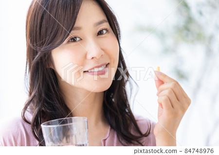 Female in a loungewear drinking capsule tablets 84748976