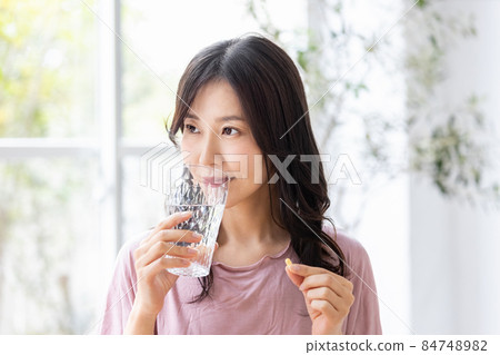 穿著休閒服的女性飲用膠囊片 84748982