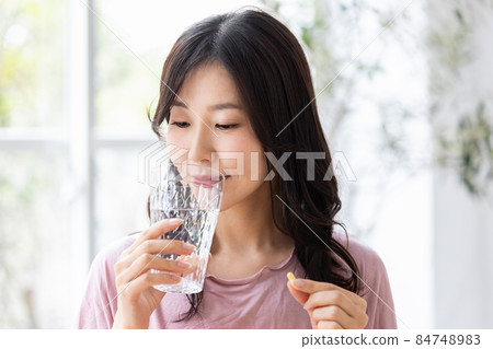 穿著休閒服的女性飲用膠囊片 穿著休閒服的女性飲用膠囊片 84748983