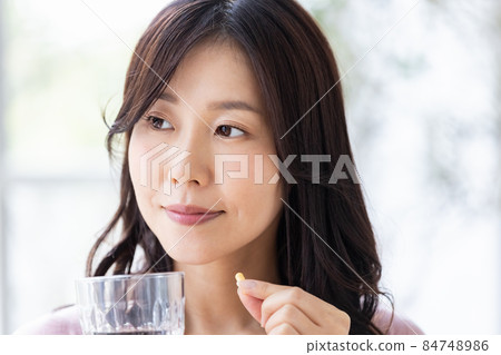 Female in a loungewear drinking capsule tablets Female in a loungewear drinking capsule tablets 84748986