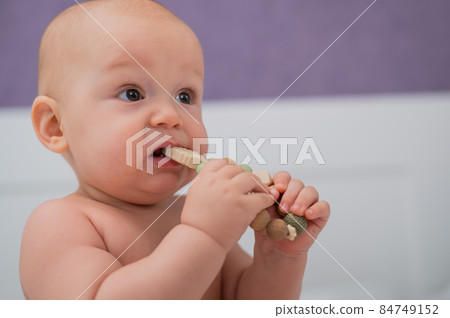 Baby boy gnaws wooden teething boxes. Eco friendly toy. Baby boy gnaws wooden teething boxes. Eco friendly toy. 84749152