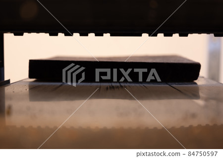 Selective focus looking into a wood planer bed raised above the board 84750597