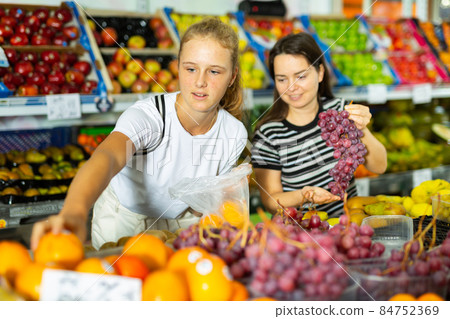 Teenage girl and her mother buying grape at grocery Teenage girl and her mother buying grape at grocery 84752369