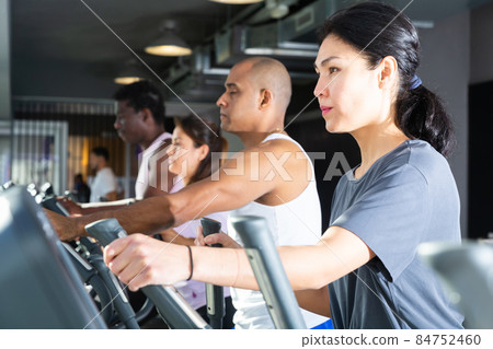 Athletic people running on elliptical trainer in fitness club 84752460