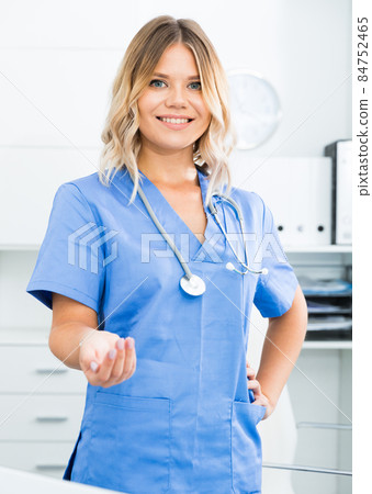 Friendly girl in doctor's uniform smiling at office Friendly girl in doctor's uniform smiling at office 84752465