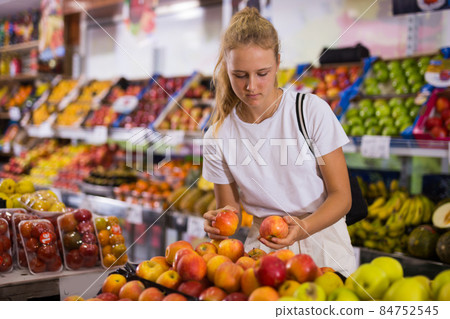Focused fifteen-year-old girl chooses ripe apples 84752545