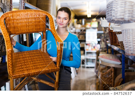 woman standing with wicker chair in shop for decor woman standing with wicker chair in shop for decor 84752637