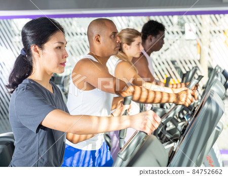 Woman training on elliptical trainer in gym 84752662