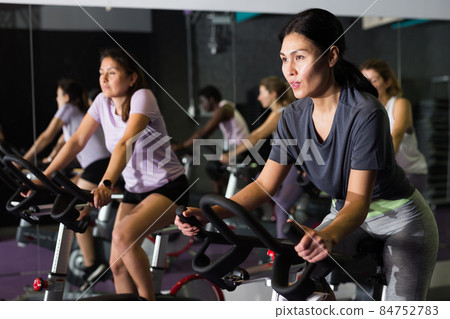 Woman ride stationary bike in fitness club Woman ride stationary bike in fitness club 84752783