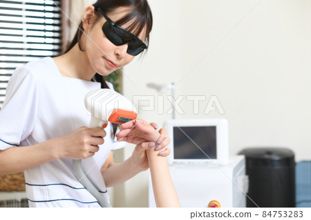 員工和女性顧客使用沙龍機器進行脫毛治療 84753283