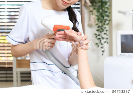 員工和女性顧客使用沙龍機器進行脫毛治療 84753287