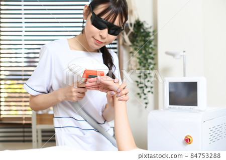 員工和女性顧客使用沙龍機器進行脫毛治療 員工和女性顧客使用沙龍機器進行脫毛治療 84753288