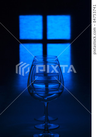 Still life with glass goblets with liquid against the background of a glowing window silhouette Still life with glass goblets with liquid against the background of a glowing window silhouette 84753741