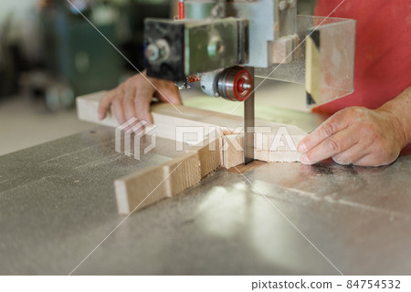 person cutting a wooden board with a band saw person cutting a wooden board with a band saw 84754532