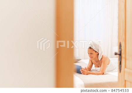 A smiling woman wrapped in towels using her digital tablet. A smiling woman wrapped in towels using her digital tablet. 84754533