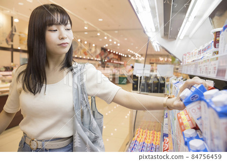 Female shopper getting milk at a supermarket Female shopper getting milk at a supermarket 84756459
