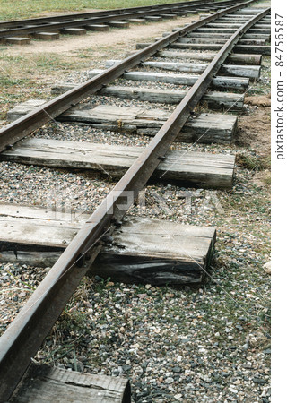 Unused old railways train line tracks wood and metal with growing grass 84756587
