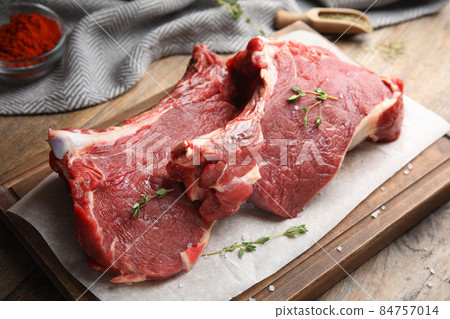 Fresh raw beef cut with thyme and salt on wooden table, closeup Fresh raw beef cut with thyme and salt on wooden table, closeup 84757014